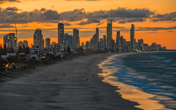 Sunset over Miami's coastline with skyscrapers lining the beach, under a vibrant cloud-filled sky, captured in HD for a striking cityscape wallpaper.