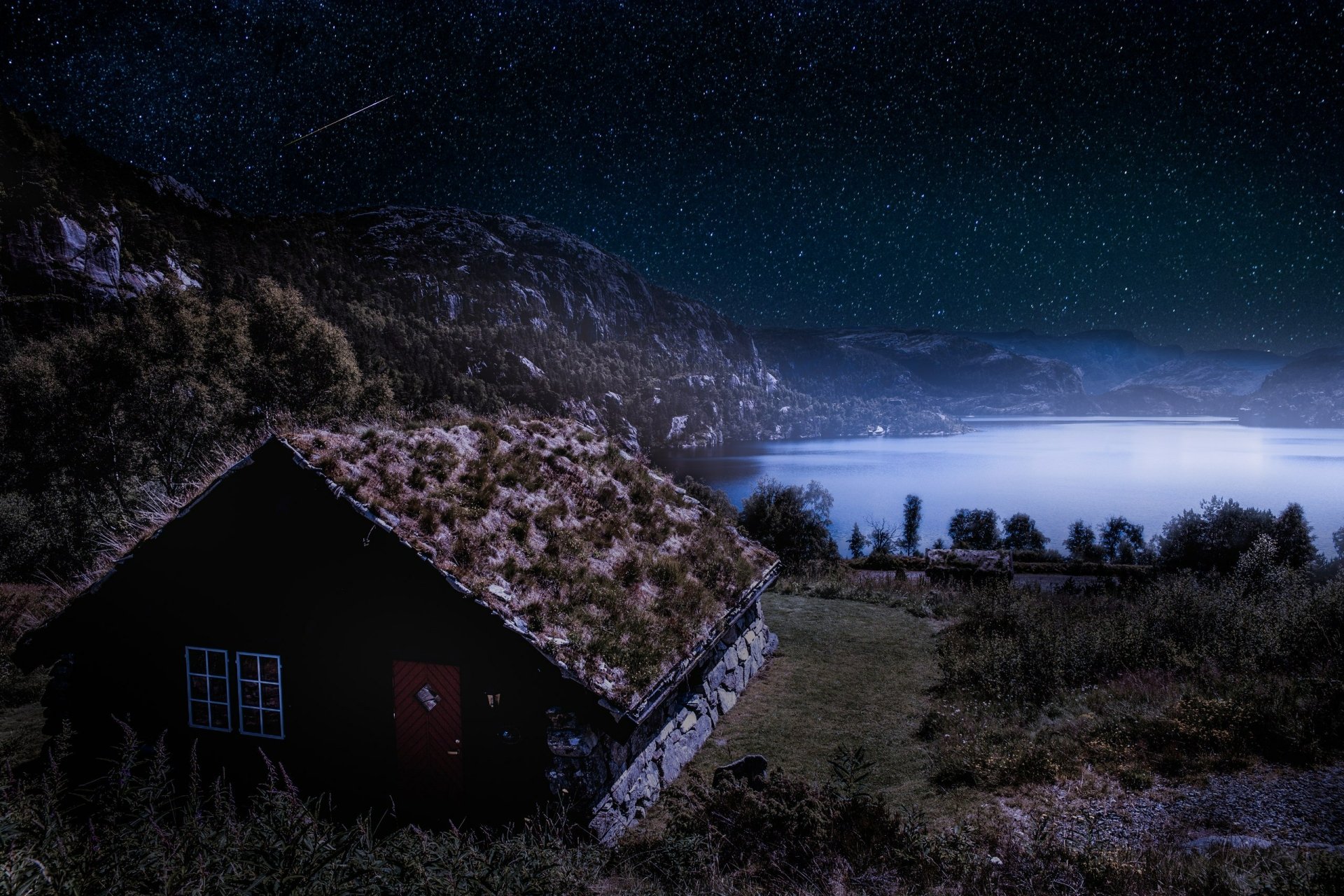 A grassy-roofed house by a Norwegian lake at night, under a star-filled sky, captured in HD for a serene desktop wallpaper background.