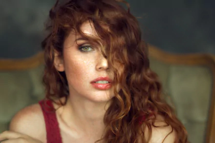 Close-up portrait of a redheaded woman model with green eyes and freckles, tousled hair partially covering her face — HD PC desktop wallpaper and background.