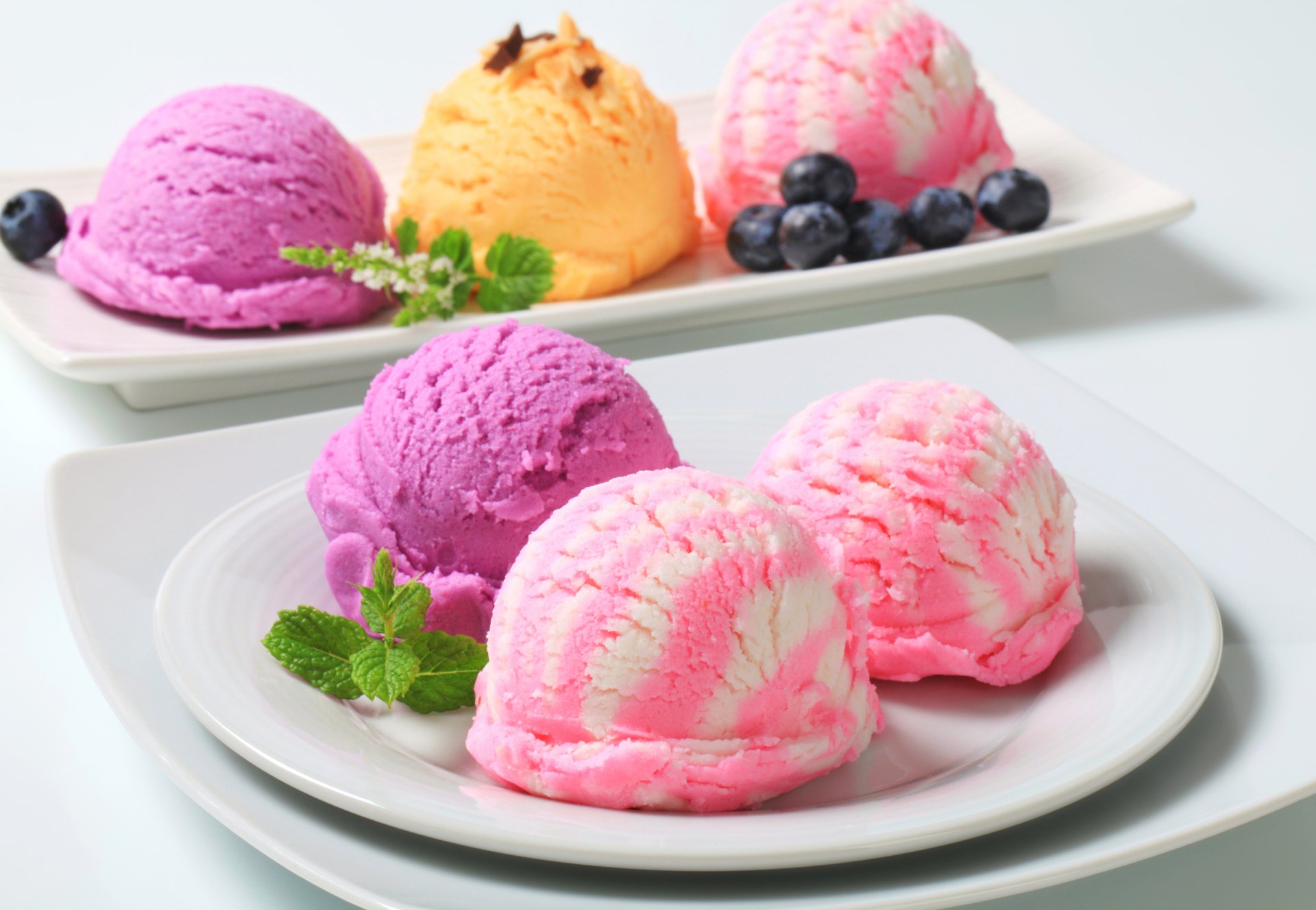 Close-up of colorful scoops of ice cream with blueberries and mint on white plates, captured in vibrant 4K Ultra HD, showcasing delicious sweets and refreshing food.