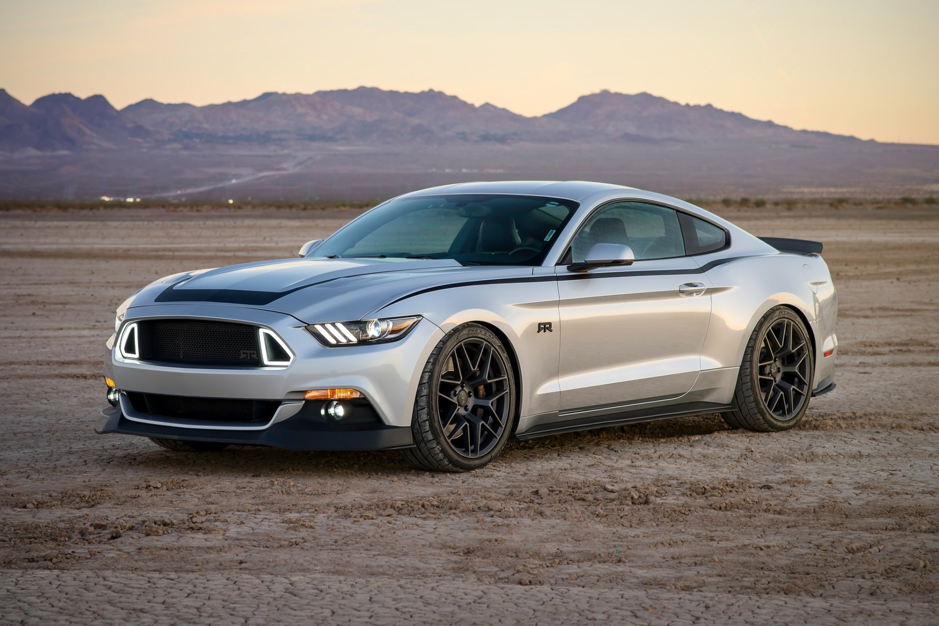 Silver Ford Mustang RTR muscle car parked on a desert landscape at sunset, showcased in vivid HD for a desktop wallpaper background.