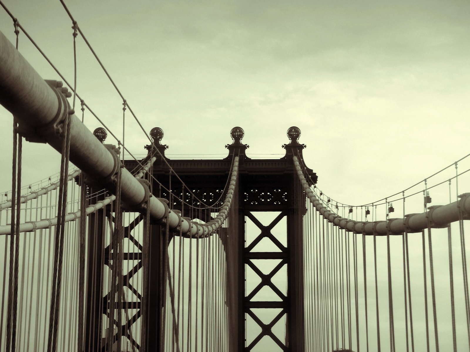 HD desktop wallpaper featuring a close-up view of the Manhattan Bridge’s suspension cables and towers under a muted sky.