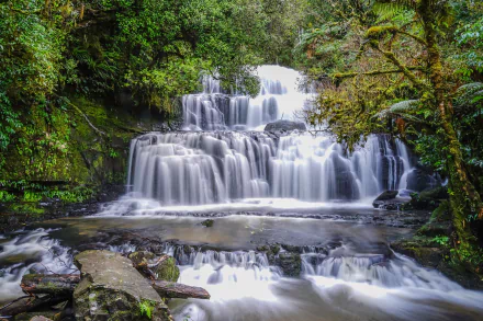 HD PC desktop wallpaper/background — multi-tiered waterfall in a lush forest, water foaming into a river over mossy rocks, capturing serene nature.