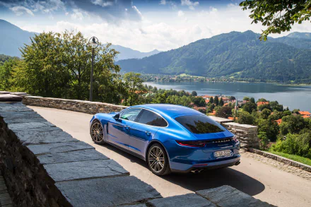 A blue Porsche Panamera Turbo parked on a scenic mountain road overlooking a lake and distant hills, captured in 4K Ultra HD for a PC desktop wallpaper.