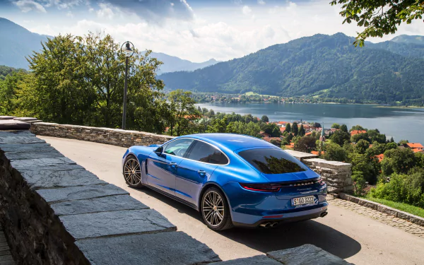 A blue Porsche Panamera Turbo parked on a scenic mountain road overlooking a lake and distant hills, captured in 4K Ultra HD for a PC desktop wallpaper.