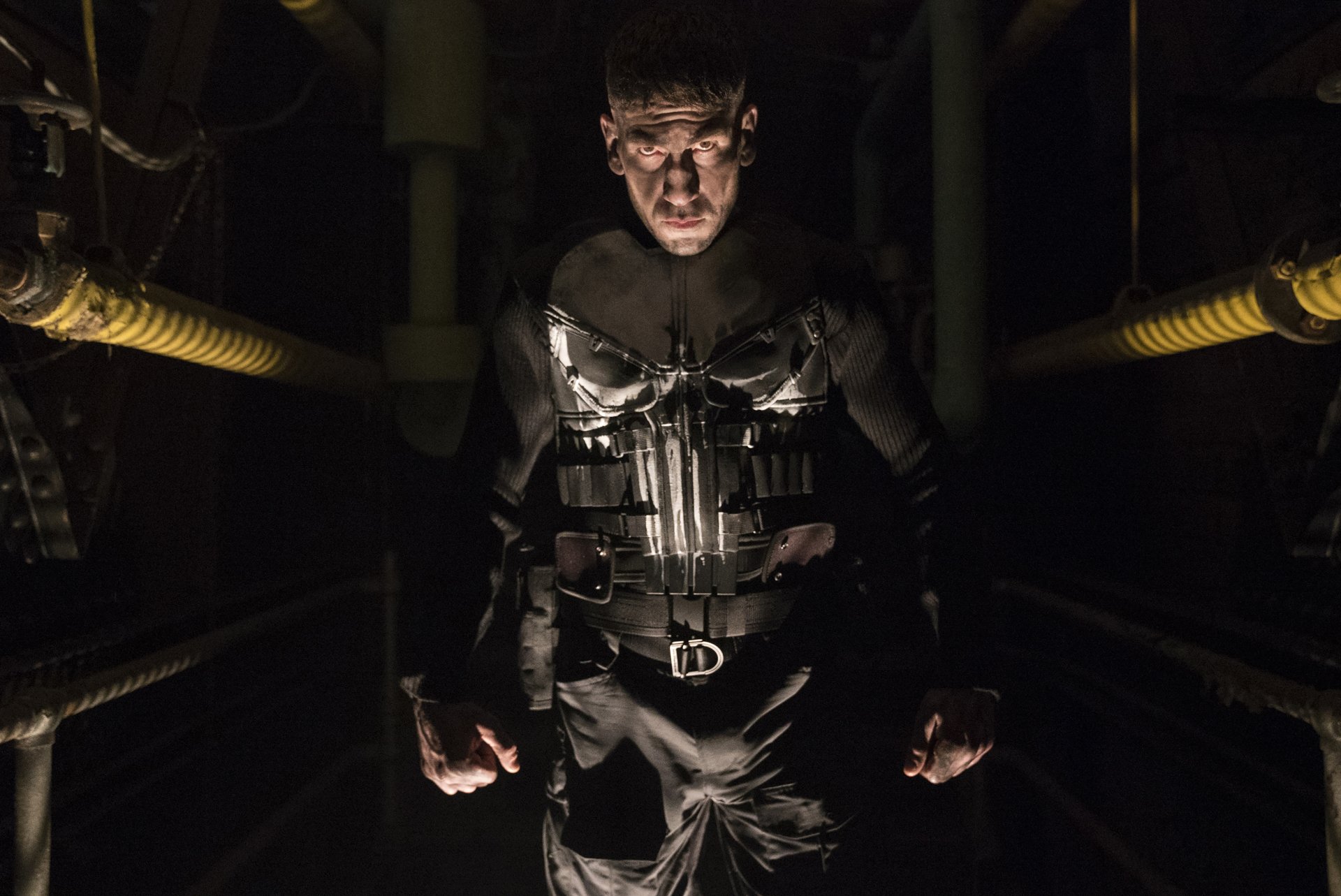 Jon Bernthal as the Punisher stands menacingly in shadows, showcasing his intense character from the TV show. This dramatic 4K Ultra HD image captures his fierce presence.