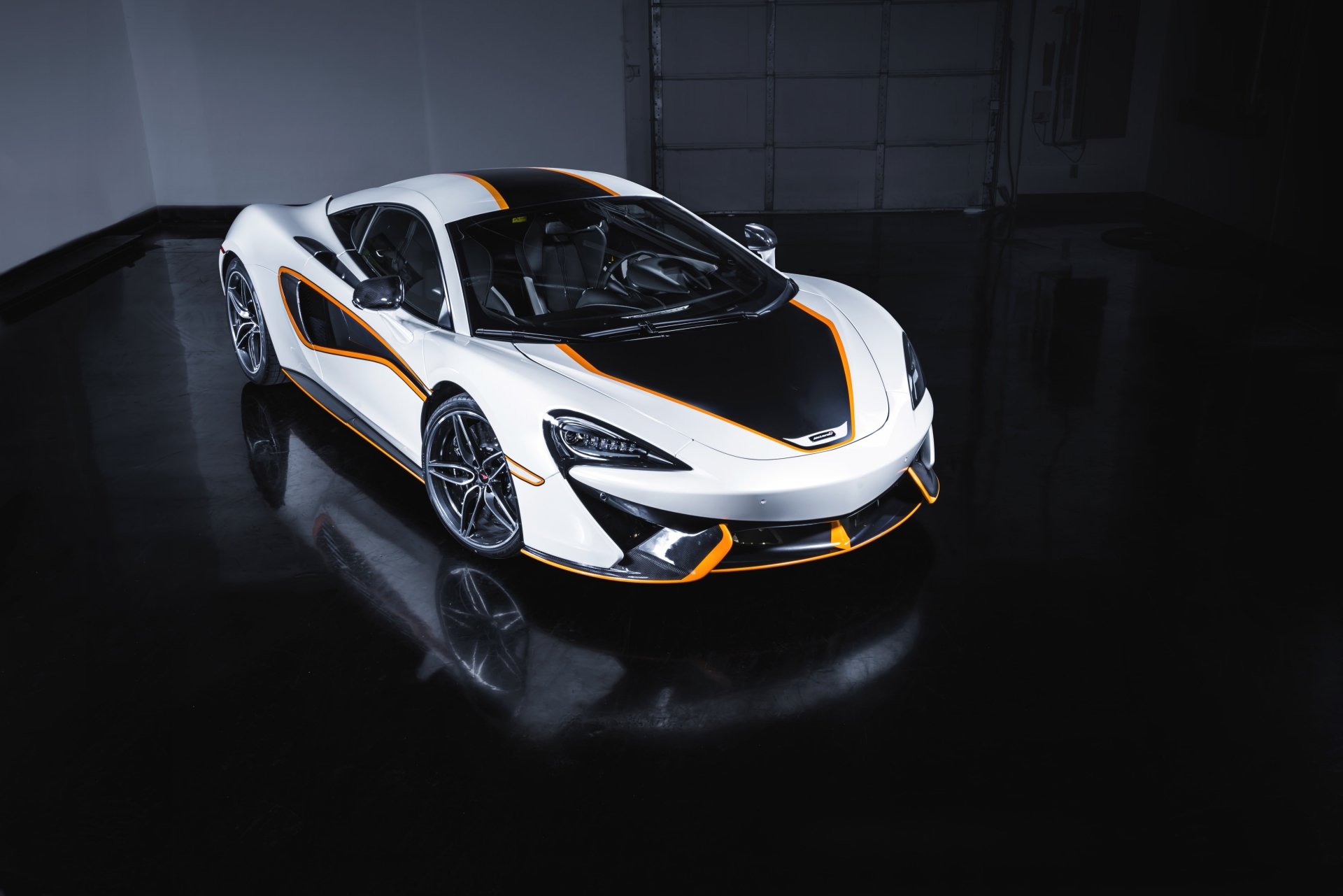 White McLaren 570S supercar with black and orange accents is showcased in a sleek, dark setting, captured in 4K Ultra HD for PC desktop wallpaper.