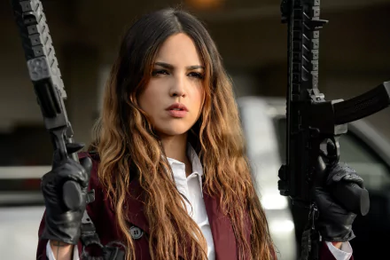 Eiza González stands confidently with two rifles, showcasing her fierce character from the movie Baby Driver. This striking HD wallpaper captures the intensity of her role.