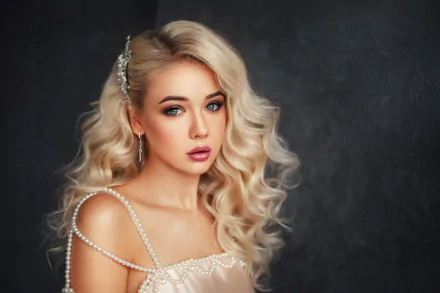 A blonde model with blue eyes and curled hair, adorned with a hair accessory and wearing lipstick, poses in a high-definition wallpaper background.