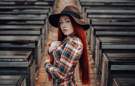 2K Quad HD PC desktop wallpaper: depth-of-field portrait of a redhead woman model with long hair, freckles and blue eyes wearing a brown hat and plaid shirt.