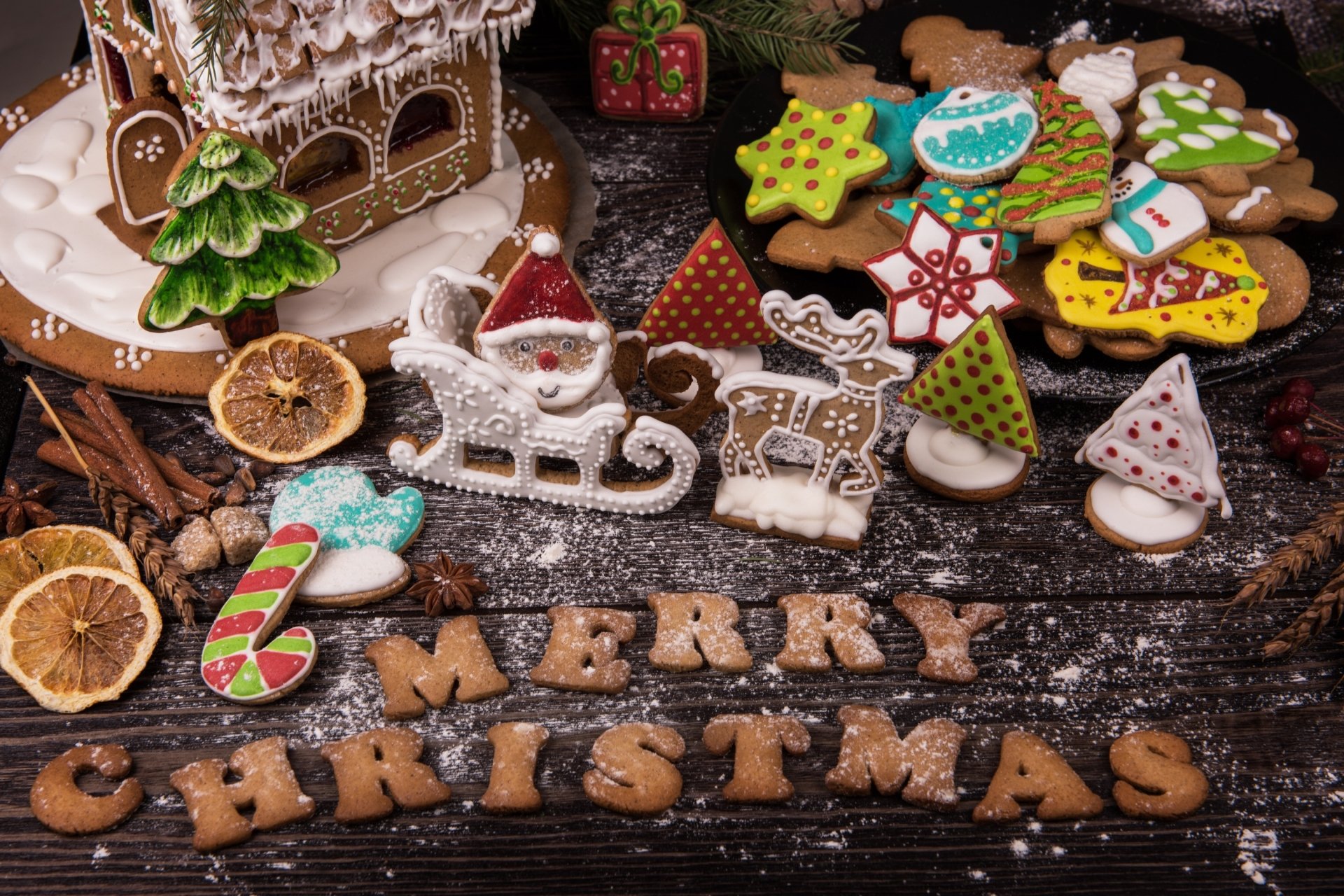 HD desktop wallpaper featuring festive gingerbread cookies, holiday decorations, and a Christmas-themed arrangement with MERRY CHRISTMAS spelled out in gingerbread letters.
