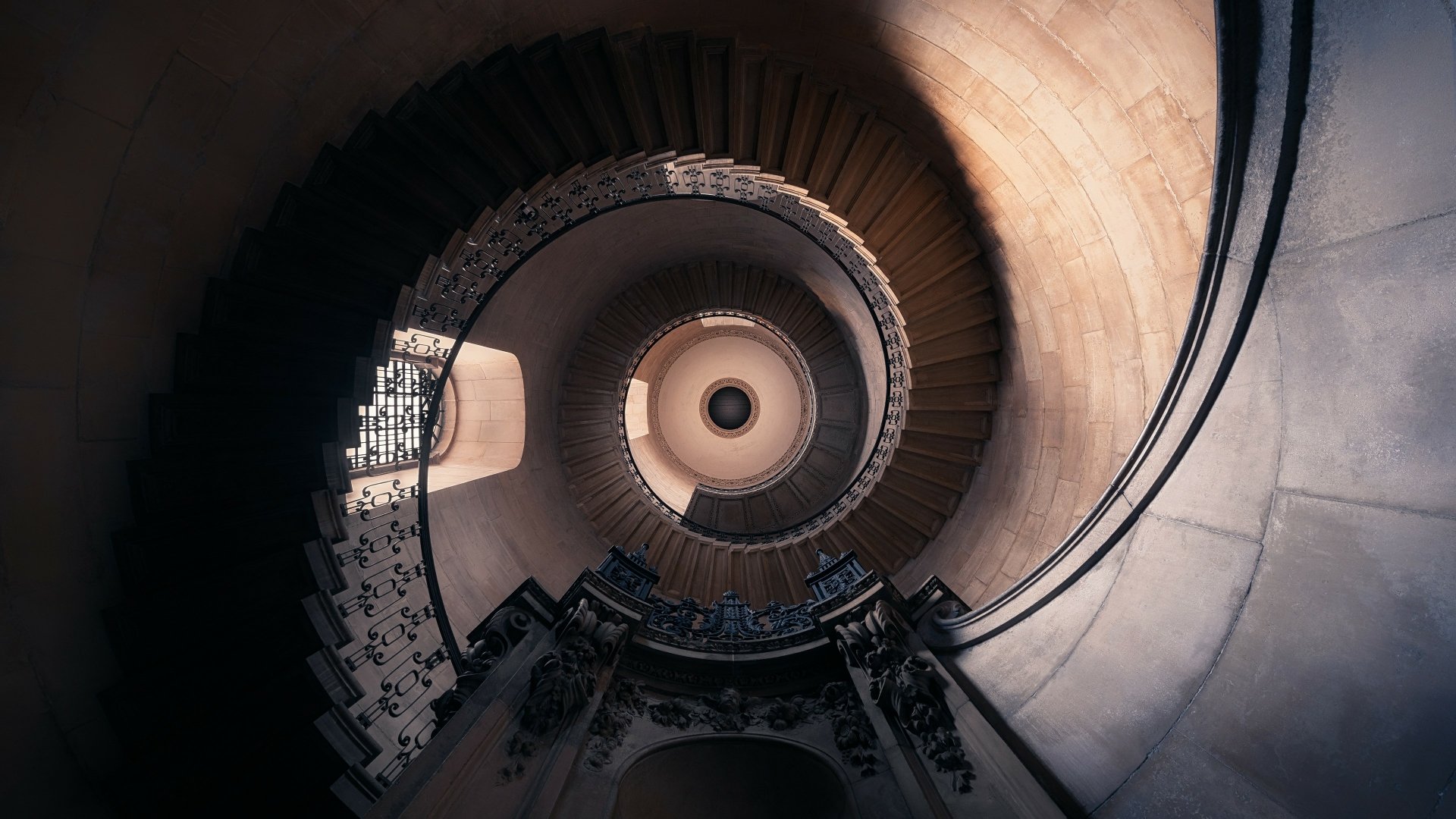 A 4K Ultra HD image of a man-made spiral staircase inside St Paul's Cathedral, showcasing intricate stairs and architectural details from a top-down perspective.
