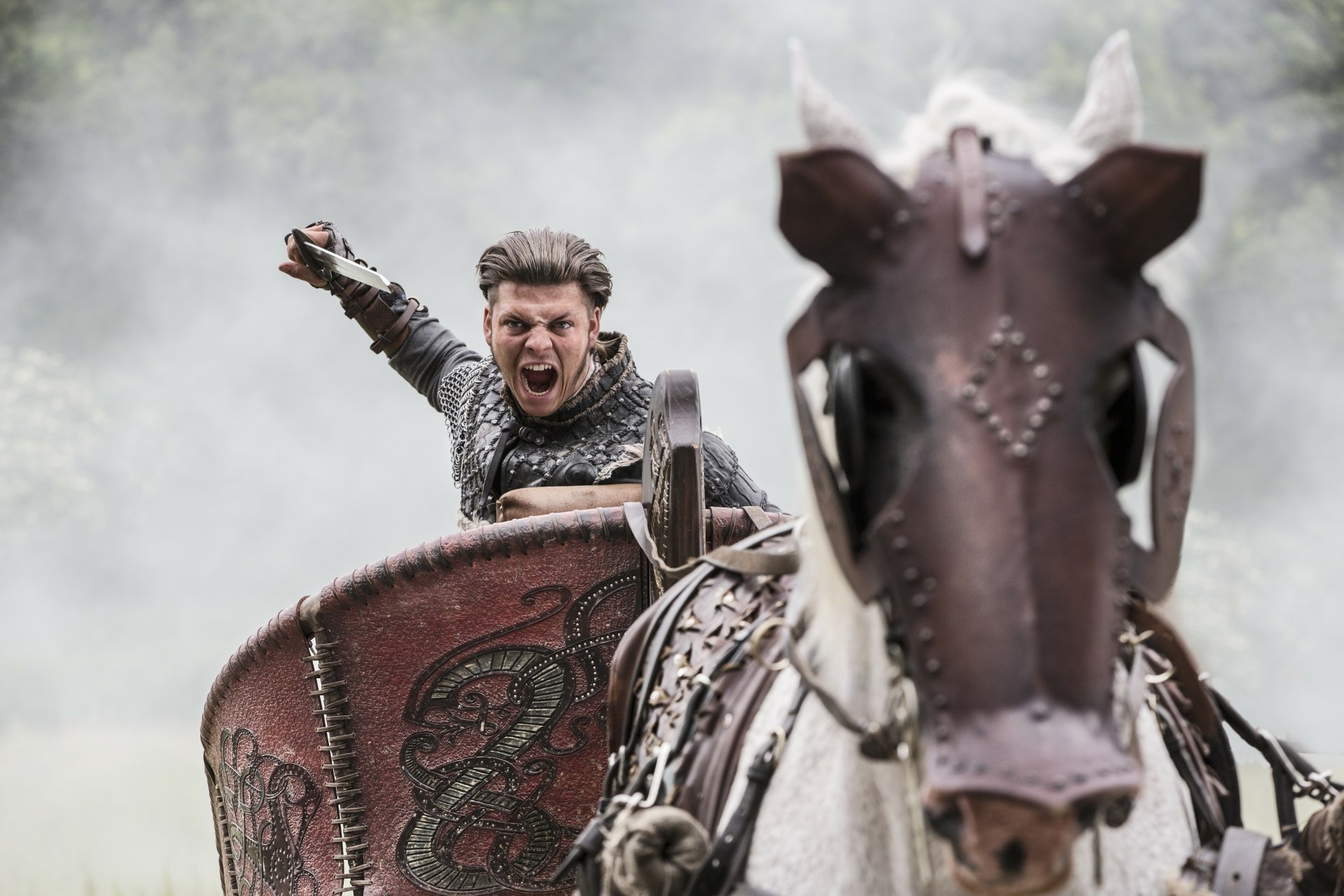 Roaring Viking warrior charging on horseback, shield raised amid mist — TV show Vikings (2013) 5K Ultra HD PC desktop wallpaper background.