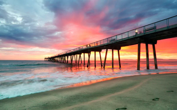 Sunset over the ocean at Hermosa Beach with a long pier extending into the sea, captured in an HD desktop wallpaper showcasing the horizon and vibrant sky.