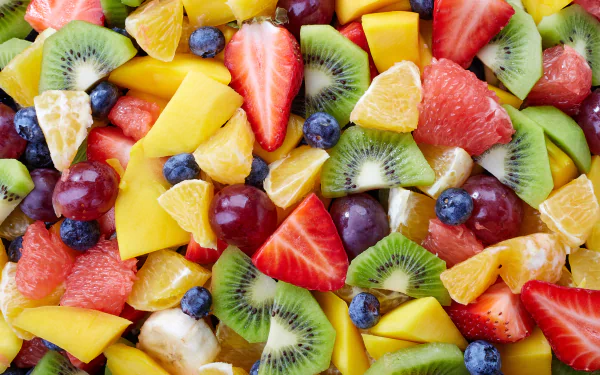A vibrant 4K Ultra HD PC desktop wallpaper featuring a colorful assortment of fresh fruit slices including strawberries, kiwi, mango, blueberries, grapes, and citrus.