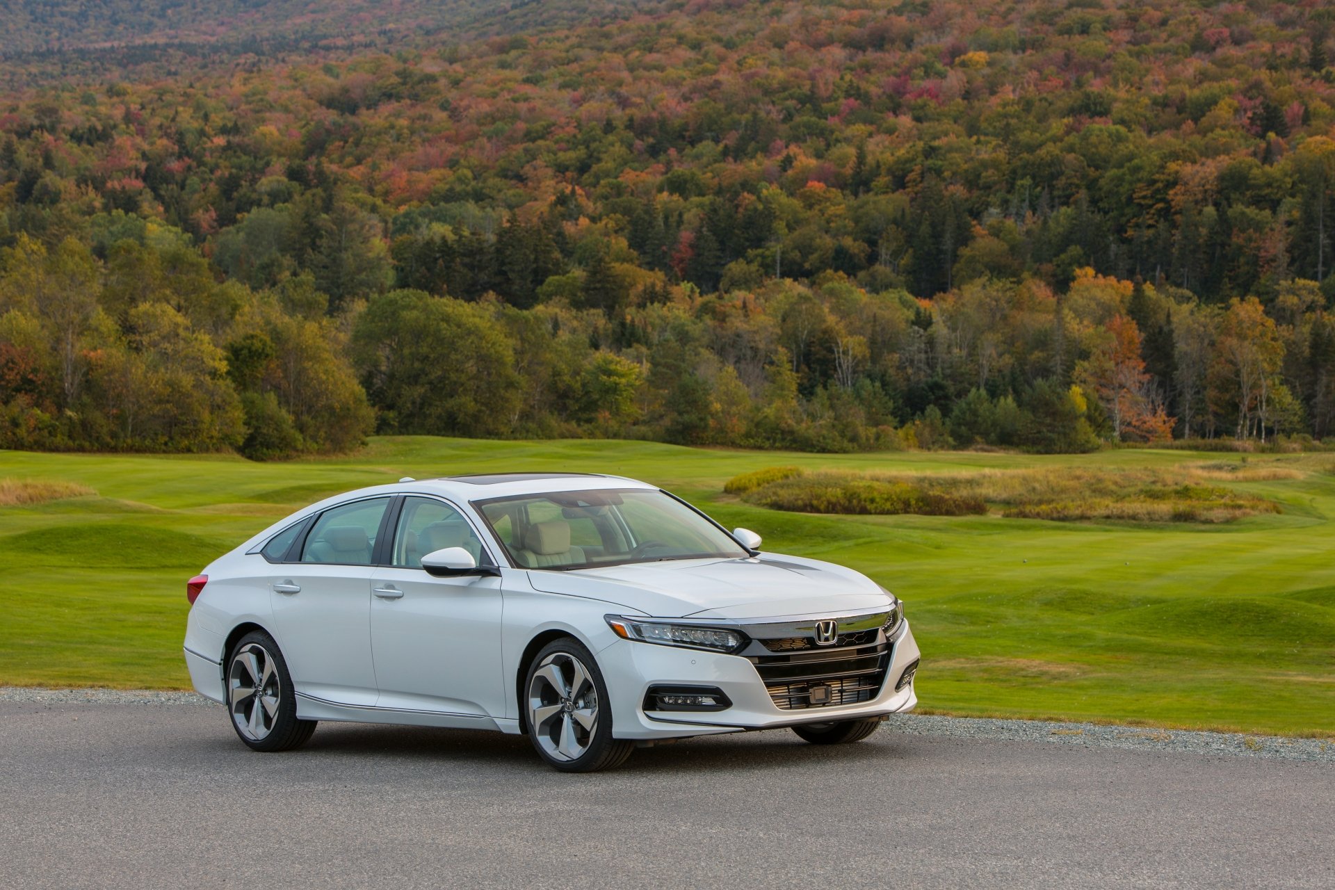 White Honda Accord compact car parked on a road with a lush green field and autumn-colored forest in the background, presented as a 4K Ultra HD desktop wallpaper.