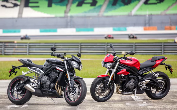 Two Triumph Street Triple motorcycles, one black and one red, parked side by side on a racetrack, featured in a 4K Ultra HD PC desktop wallpaper background.