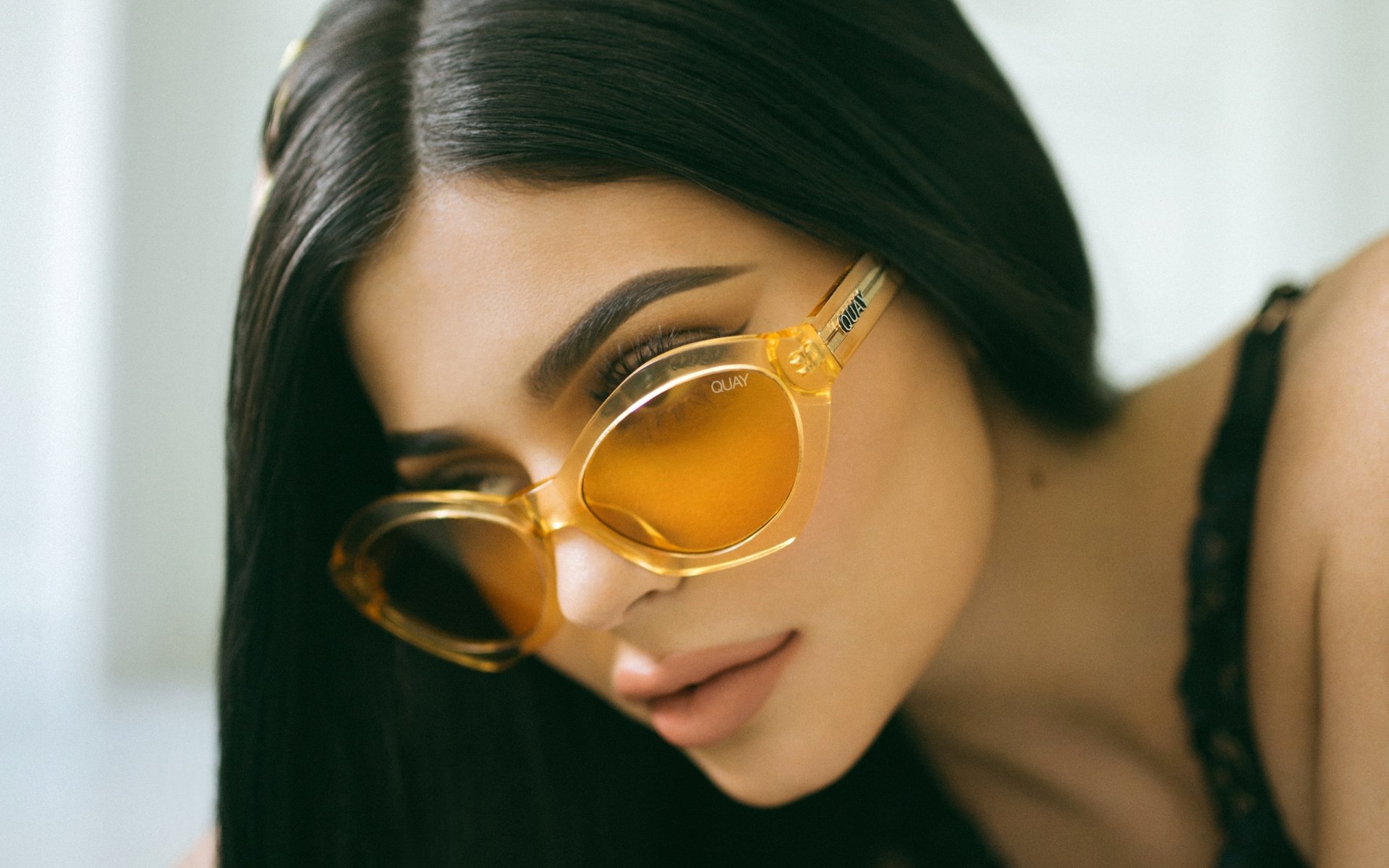 HD desktop wallpaper featuring a close-up of American brunette model and celebrity Kylie Jenner wearing stylish yellow sunglasses.