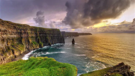 HD PC desktop wallpaper: Cliffs of Moher, Ireland — rugged green coastline and sea meeting the Atlantic Ocean under a dramatic horizon sky.