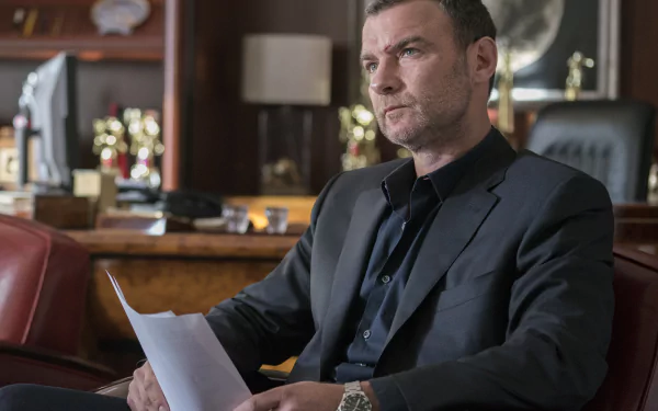 HD desktop wallpaper featuring a character from Ray Donovan seated in a leather chair with a pensive expression, holding a document, set in an elegant room.