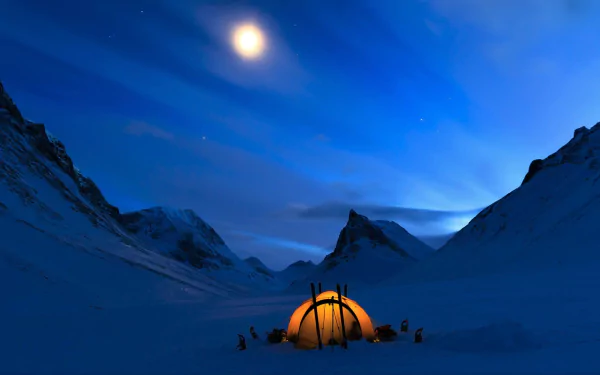 A glowing tent set against a snowy mountain under a bright moonlit winter night, captured in an HD photography desktop wallpaper.