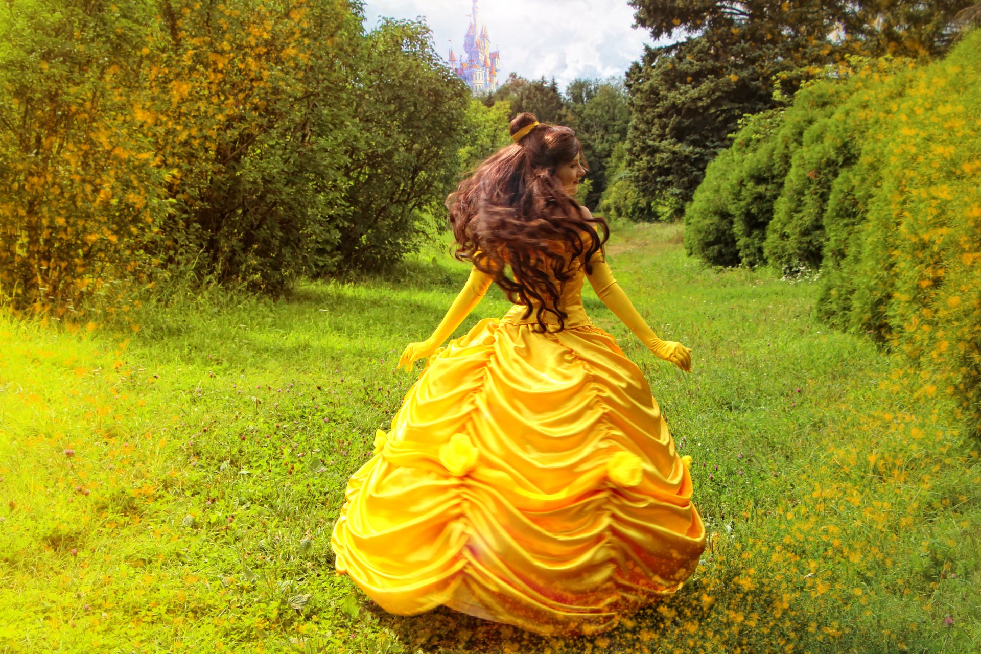 A woman in a vibrant yellow Beauty and the Beast (1991) cosplay dress stands in a lush green field under a bright sky, captured in 4K Ultra HD for a PC desktop wallpaper.