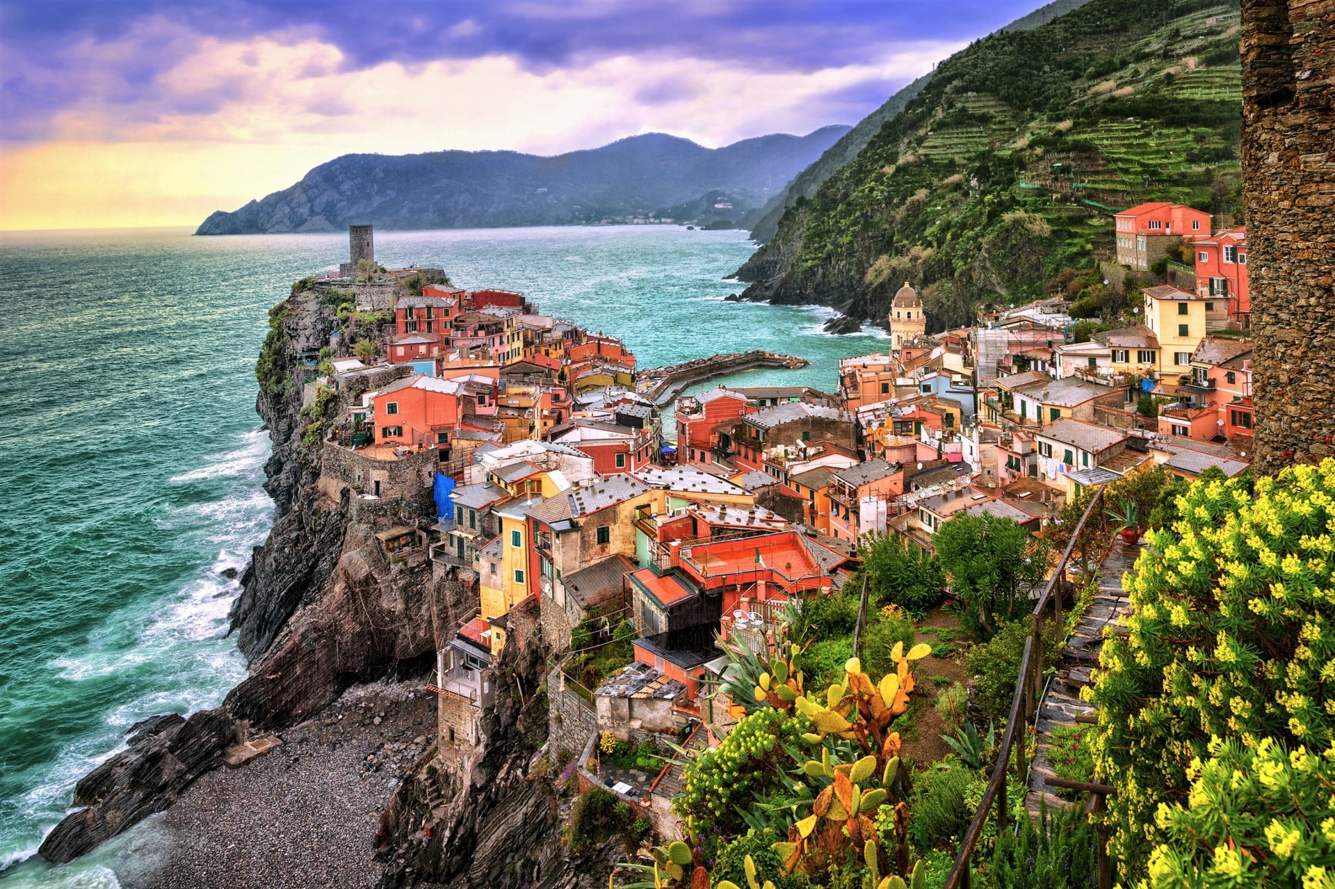 Vibrant 2K Quad HD PC desktop wallpaper/background: Vernazza, Cinque Terre, Italy — colorful man-made houses and town perched on cliffs above the sea with mountains in the background.