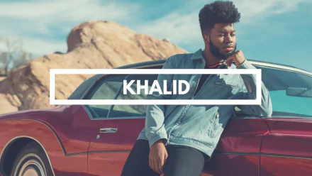 HD desktop wallpaper featuring a thoughtful individual leaning on a red car with a desert backdrop, tagged with Khalid.