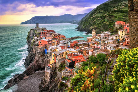 Vibrant 2K Quad HD PC desktop wallpaper/background: Vernazza, Cinque Terre, Italy — colorful man-made houses and town perched on cliffs above the sea with mountains in the background.
