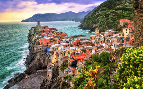 Vibrant 2K Quad HD PC desktop wallpaper/background: Vernazza, Cinque Terre, Italy — colorful man-made houses and town perched on cliffs above the sea with mountains in the background.