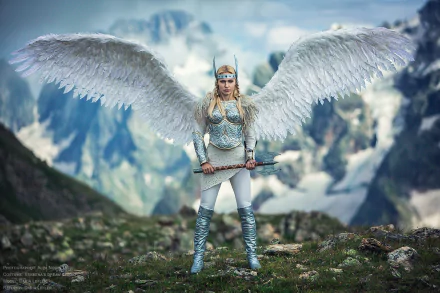 HD PC desktop wallpaper featuring a woman in detailed cosplay as a winged warrior with armor and a sword, set against a mountainous backdrop.