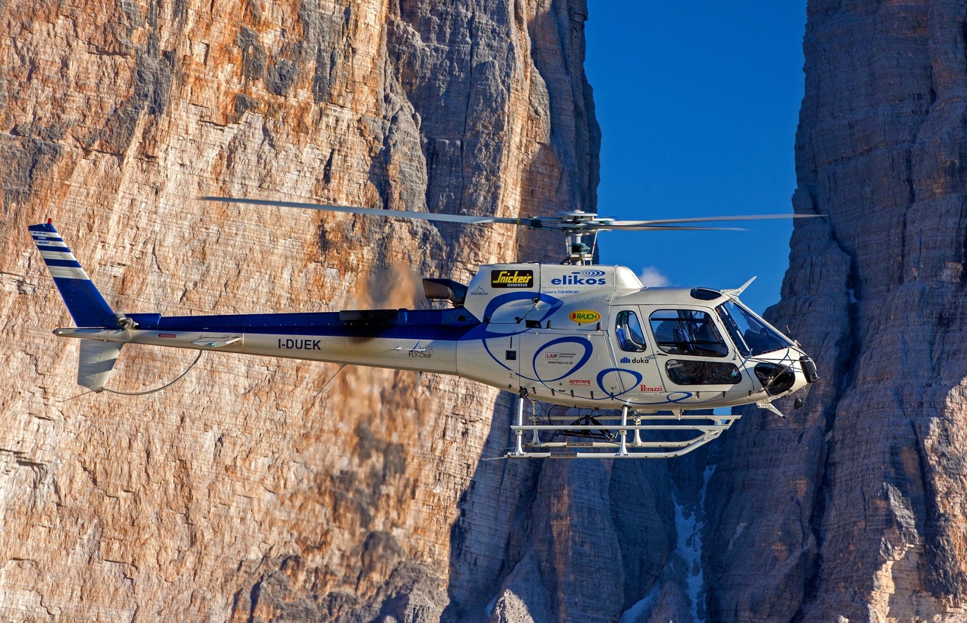Eurocopter AS350 Écureuil helicopter flying between rugged cliffs, captured in HD for a detailed PC desktop wallpaper and background.