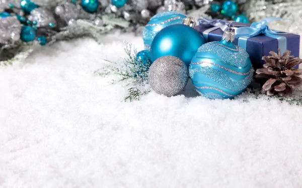 Christmas ornaments and blue gift boxes rest on snow, surrounded by pine cones and festive holiday decorations, presented in 4K Ultra HD desktop wallpaper quality.