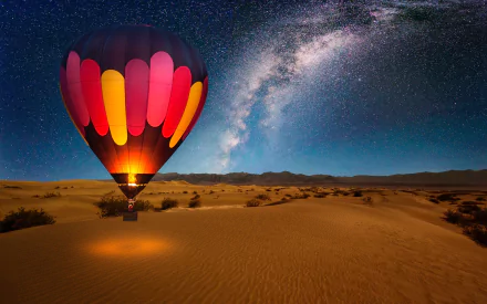 A hot air balloon glows brightly in a desert under a starry sky and the Milky Way. An ideal HD desktop wallpaper and background.