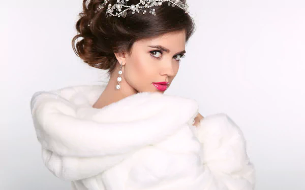 Brunette model in diamond earrings and pink lipstick, wrapped in a white fur stole, captured in a 4K Ultra HD desktop wallpaper and background.