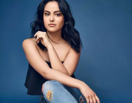 HD desktop wallpaper featuring actress and celebrity Camila Mendes with black hair and brown eyes against a solid blue background.