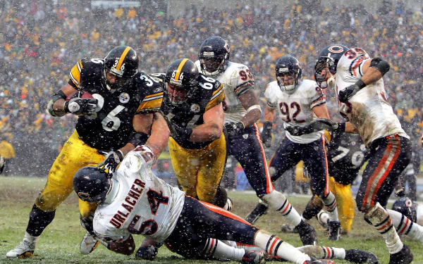 Pittsburgh Steelers action shot in heavy snow during an NFL game - dynamic sports HD PC desktop wallpaper/background showing a rushing play and intense tackle.