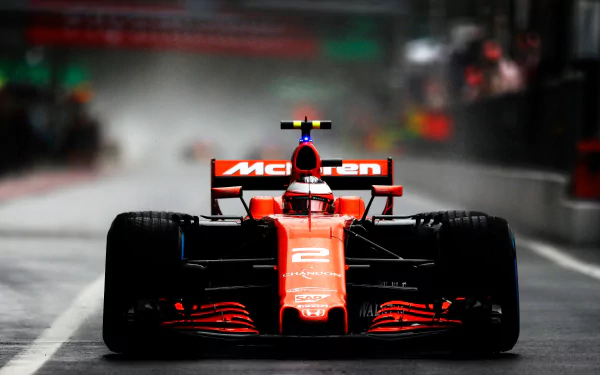F1 sports 4K Ultra HD PC desktop wallpaper/background: low-angle red McLaren F1 car racing through a wet pit lane, dramatic spray, reflections and moody lighting.