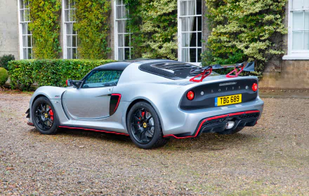 Silver Lotus Exige supercar parked beside a building, captured in 4K Ultra HD, showcasing sleek design and sporty details as a PC desktop wallpaper background.