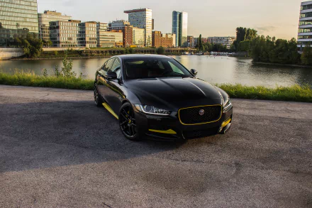 Black Jaguar XE car parked on waterfront pavement with city skyline at sunset — 4K Ultra HD PC desktop wallpaper featuring a sleek Jaguar vehicle.