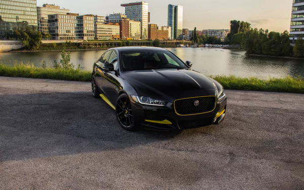Black Jaguar XE car parked on waterfront pavement with city skyline at sunset — 4K Ultra HD PC desktop wallpaper featuring a sleek Jaguar vehicle.