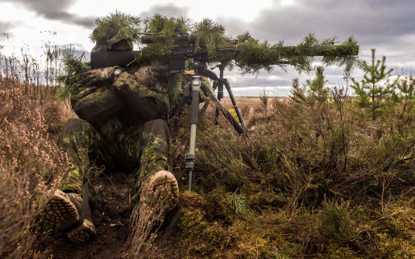 A soldier in camouflage gear aims a sniper rifle while lying on the ground in a natural outdoor setting, showcasing military precision and stealth.