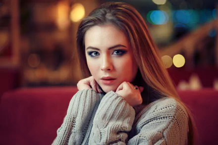 Close-up of a brunette woman with long hair and blue eyes, wearing a cozy sweater, captured in 4K Ultra HD with a soft bokeh background and shallow depth of field.
