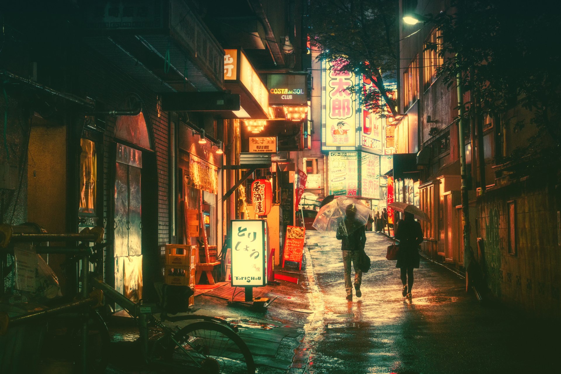 Neon-lit night scene of a city in Japan, showcasing a rain-soaked street with glowing signs and a couple walking through. HD wallpaper captures the vibrant and atmospheric essence of urban life.
