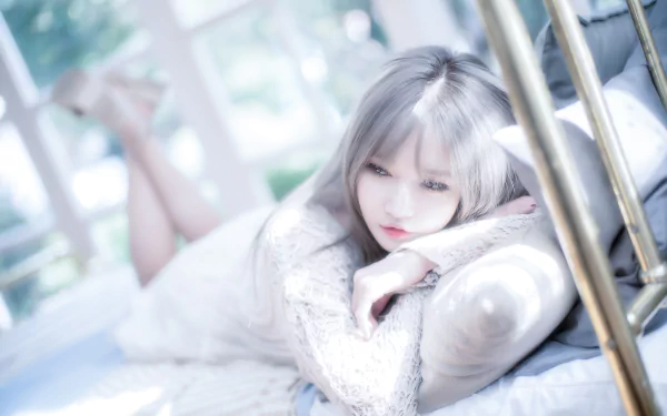 HD desktop wallpaper of a woman with white hair reclining on a bed, posed like a model in soft focus with a serene expression.
