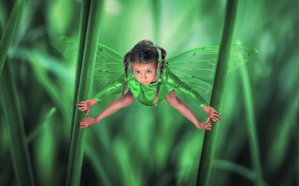 HD artistic wallpaper of a cute little girl transformed into a green fairy with delicate wings, surrounded by large grass blades in a magical, vibrant setting.