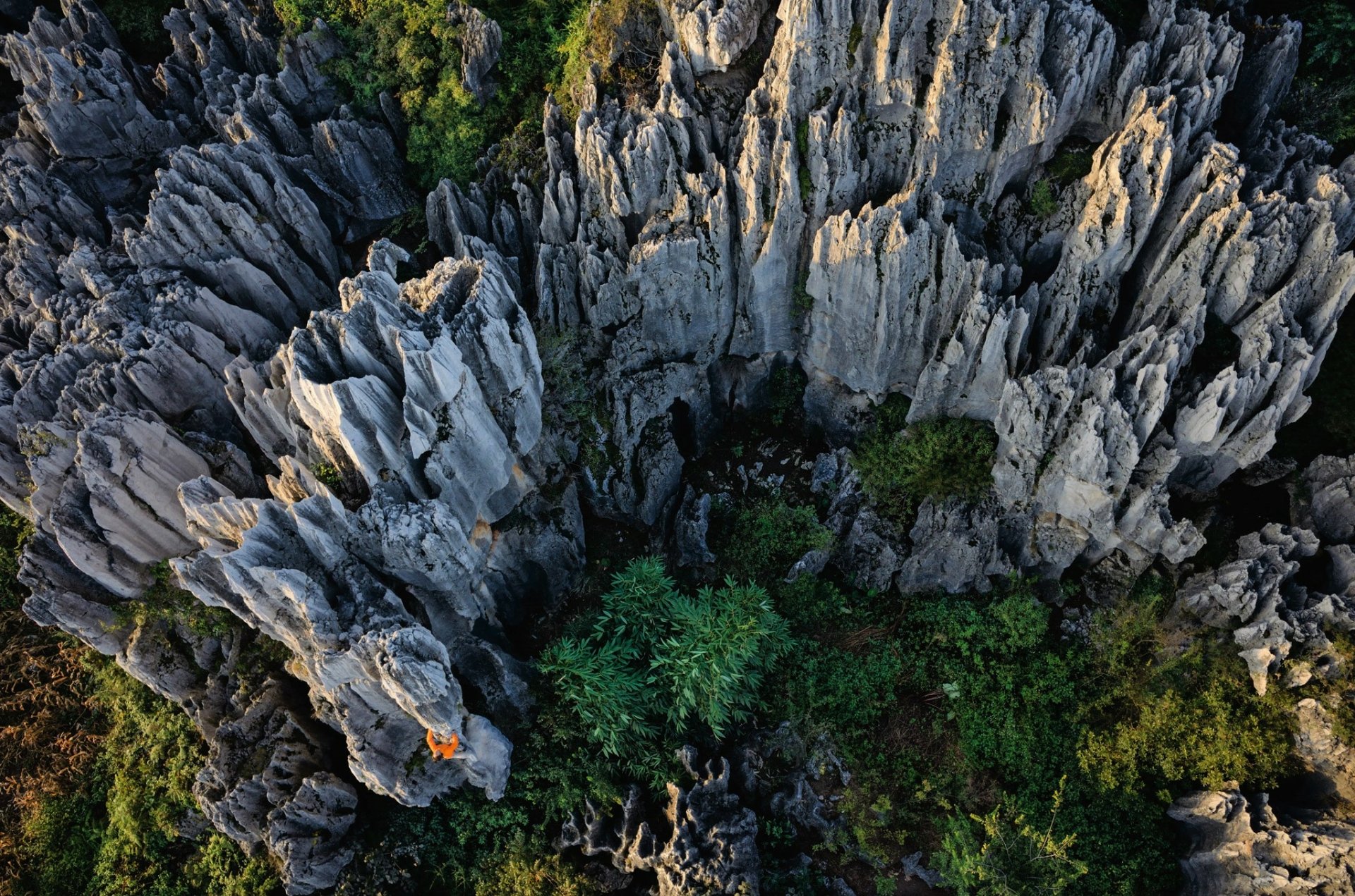 Aerial view of jagged stone formations and green vegetation in a natural landscape in China, presented as an HD PC desktop wallpaper background.