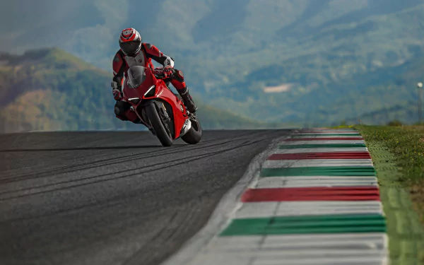 HD desktop wallpaper featuring a Ducati motorcycle in action on a race track, with a scenic mountain backdrop.