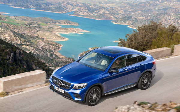 Blue Mercedes‑Benz GLC‑Class SUV driving on a mountain road above a turquoise reservoir — 4K Ultra HD PC desktop wallpaper
