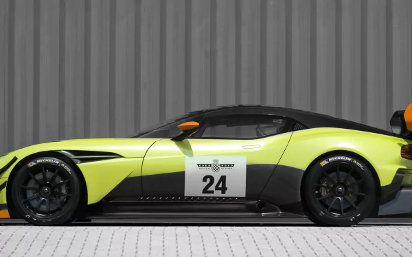 Aston Martin Vulcan AMR Pro hypercar race car (no. 24) in lime and black, side profile against a corrugated wall — 4K Ultra HD PC desktop wallpaper/background.